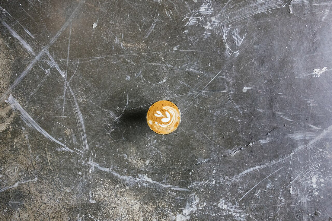 A single cup of coffee on a dark scratched concrete surface