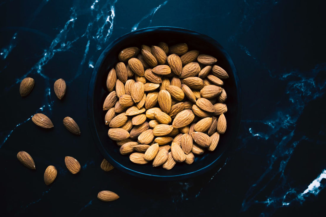 Almonds in a black bowl on dark marble, one of the richest food sources of vitamin E
