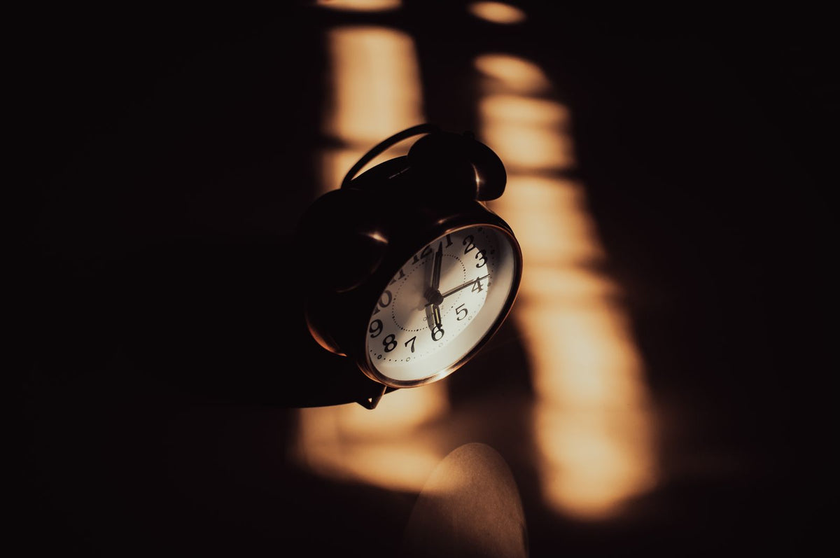 Alarm clock in a darkened room lit by a narrow strip of low evening light