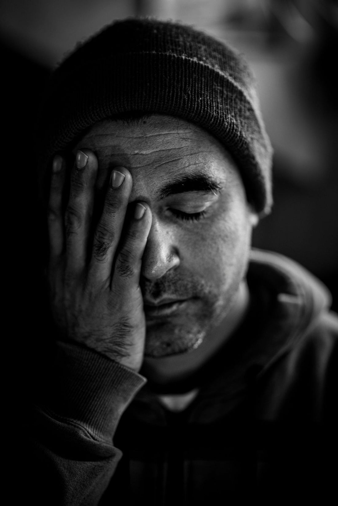 Tired man rubbing his eyes in low light, drowsy after taking a supplement
