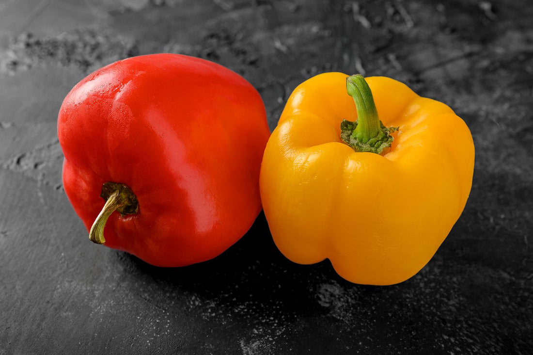Red and yellow bell peppers on a dark slate surface