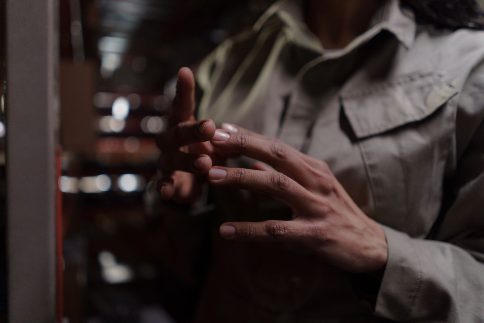 Close-up of a person's hands in low light, fingertips touching