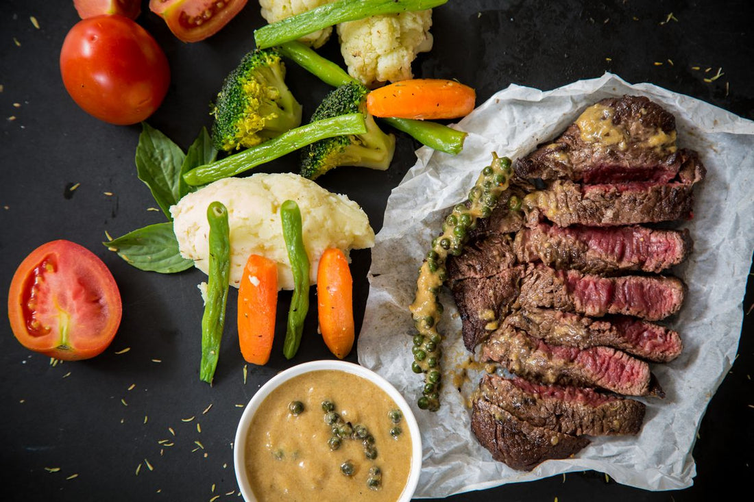 Sliced cooked steak and vegetables on a dark surface, a complete source of essential amino acids