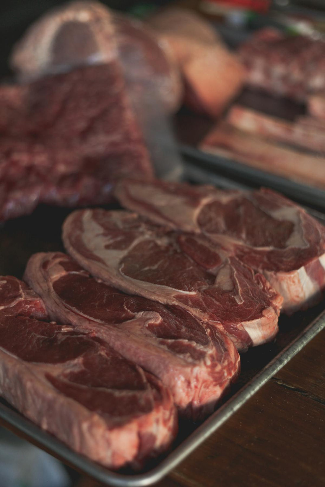 Raw marbled beef steaks on a dark tray, a dietary source of taurine