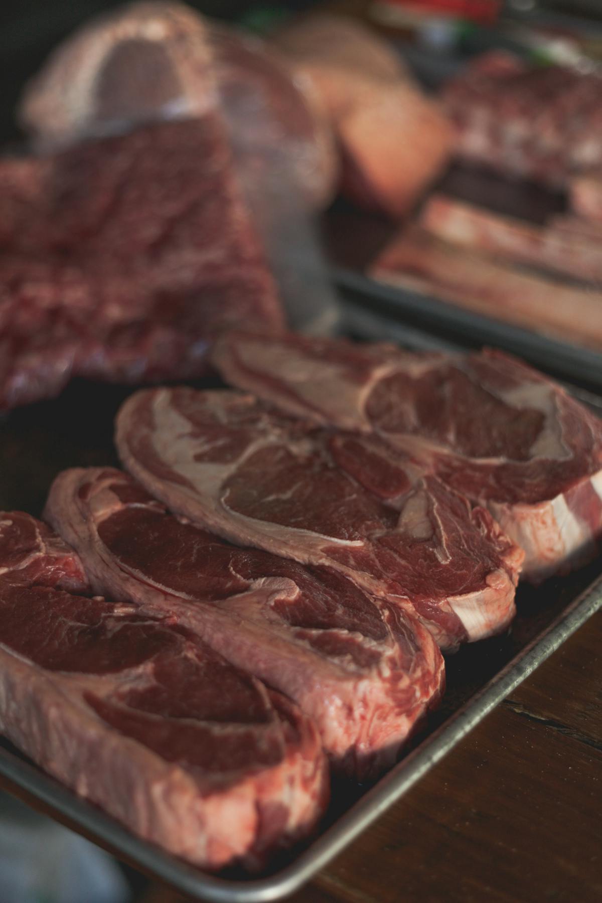 Raw marbled beef steaks on a dark tray, a dietary source of taurine