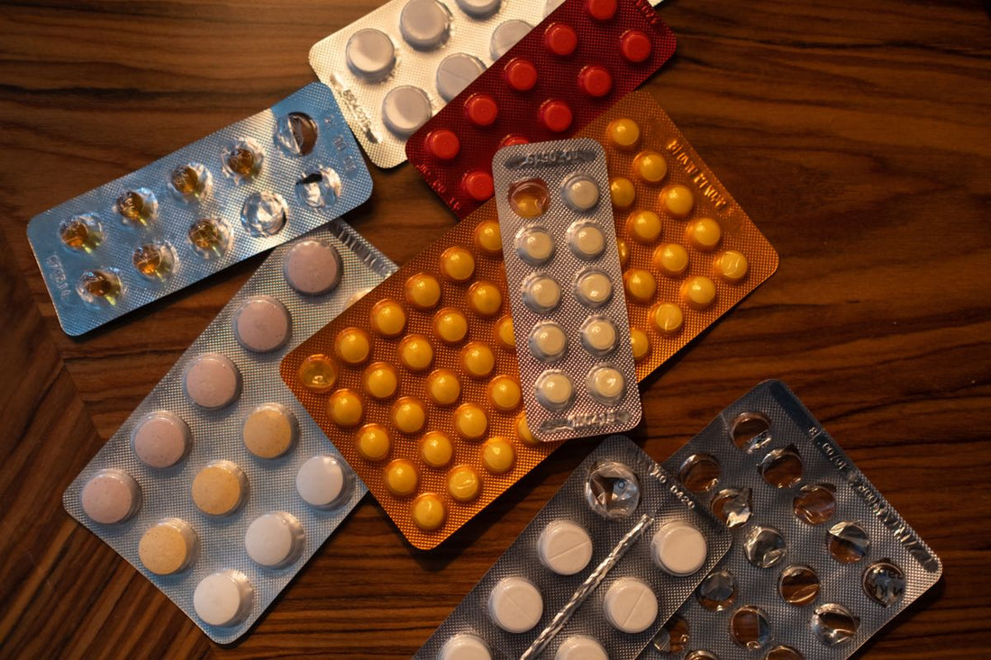 Blister packs of assorted tablets on a dark wooden surface