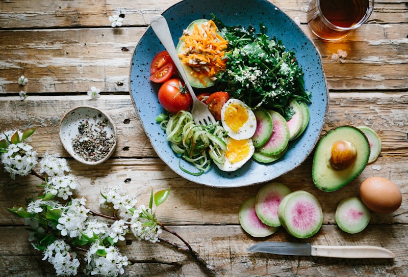 Green supplement powder in a scoop next to a glass of mixed greens drink
