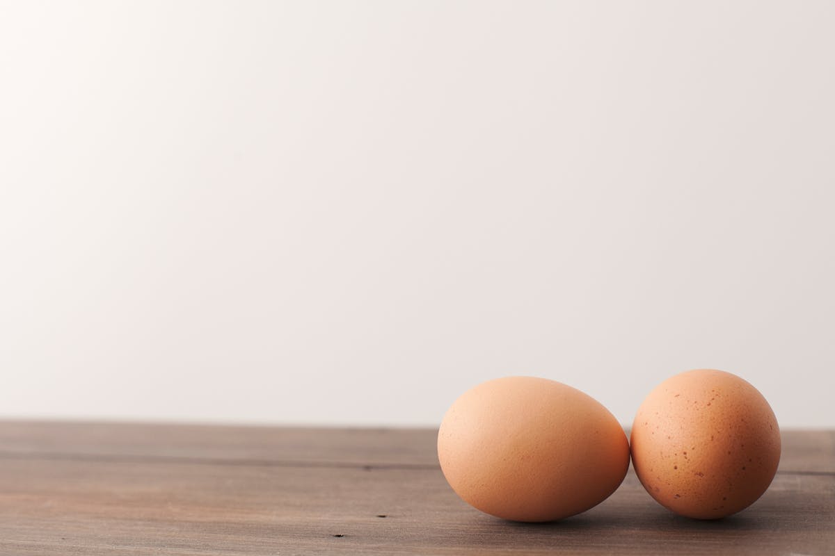 Two brown eggs on a wooden table, the best common dietary source of choline