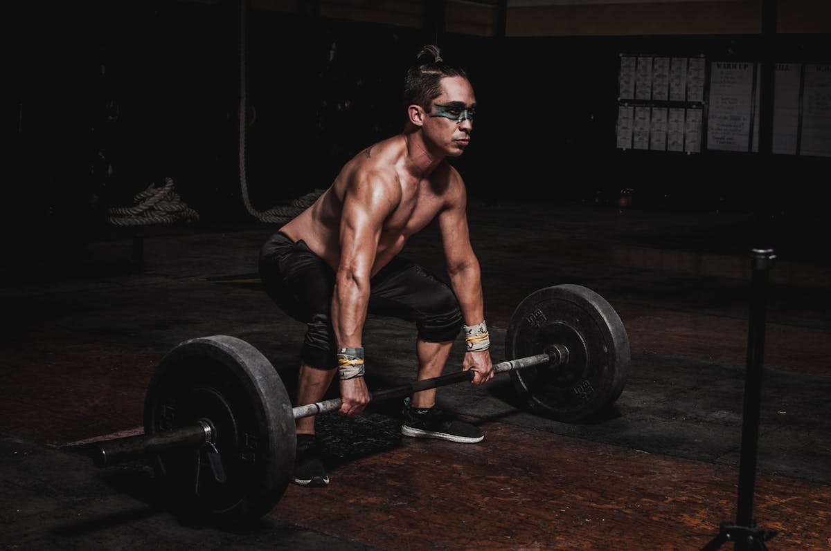 shirtless man lifting barbell gym