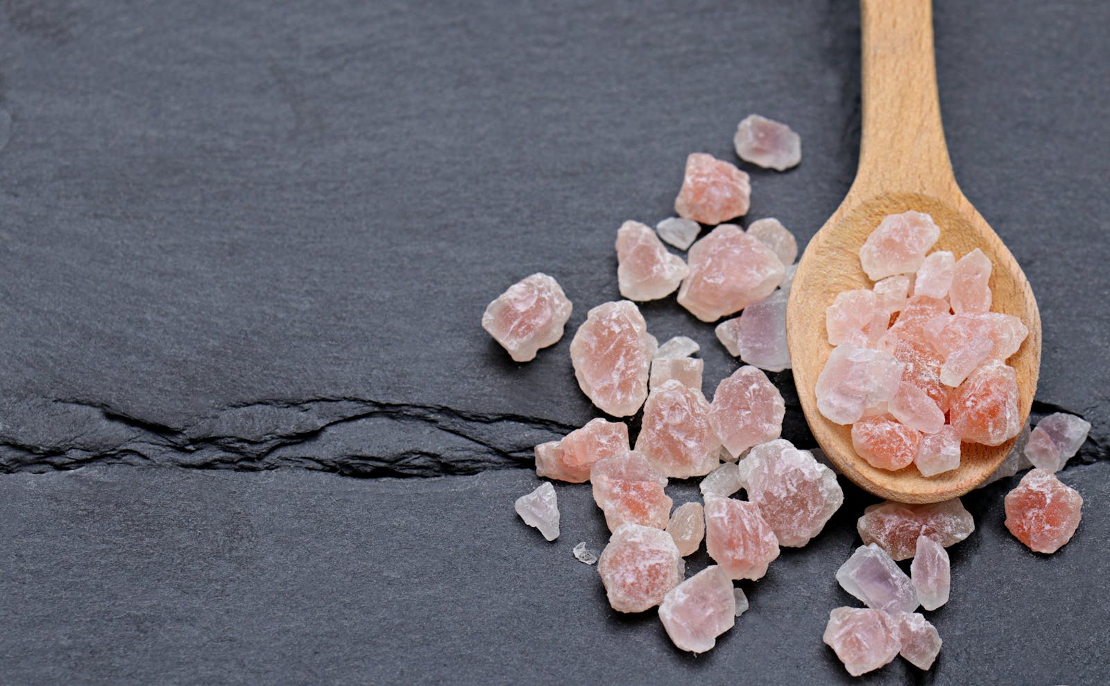 Pink Himalayan salt crystals on dark slate, electrolyte minerals for leg cramps