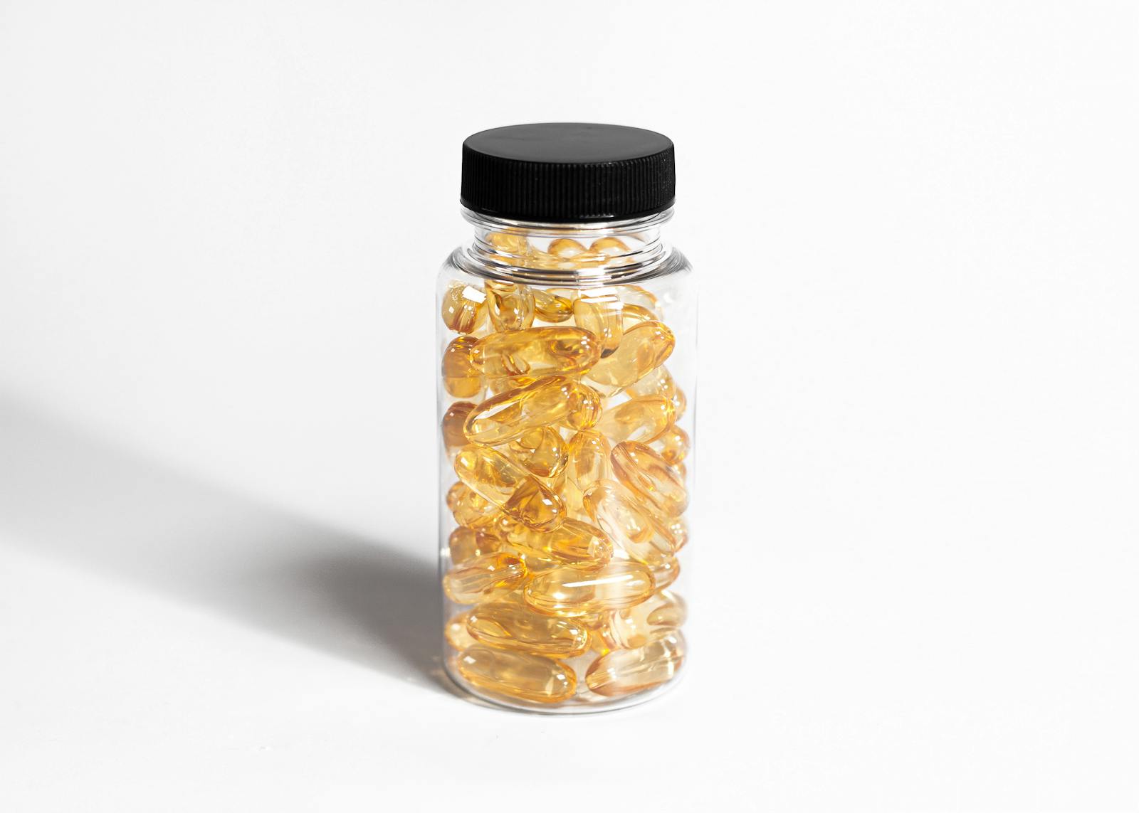 Yellow vitamin D3 softgel capsules in a clear supplement bottle