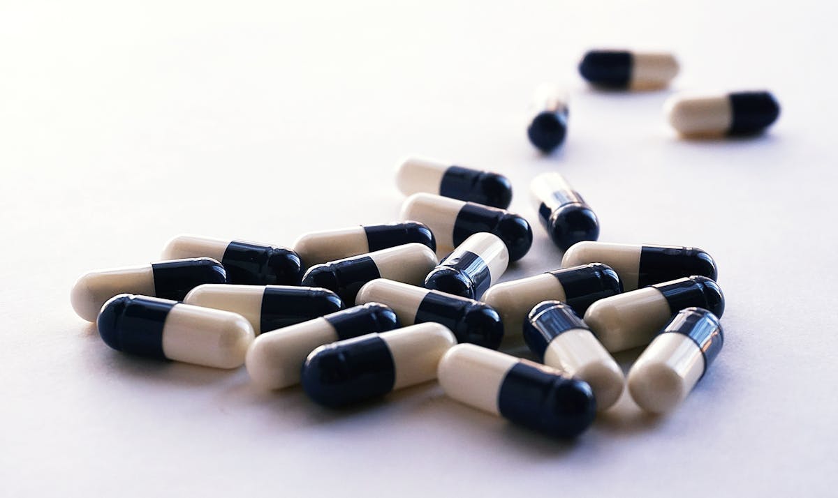 Multivitamin capsules in two-tone black and white pellets, illustrating a daily multi