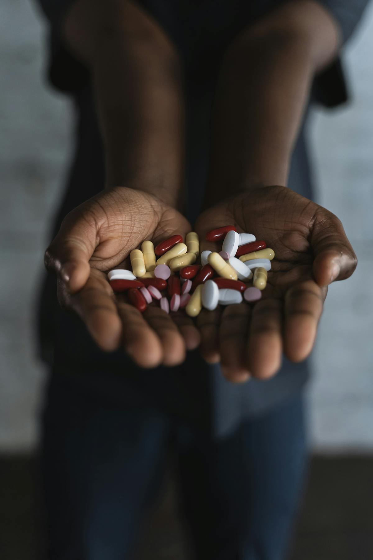 Hands holding an assortment of supplement capsules