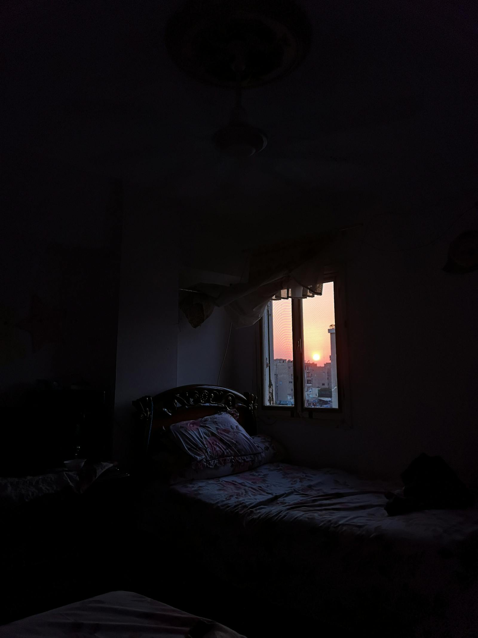 Dark bedroom at dusk with sunset visible through window, illustrating sleep onset and glycine for sleep